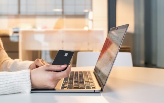 a woman sitting in front of a laptop computer holding a cell phone