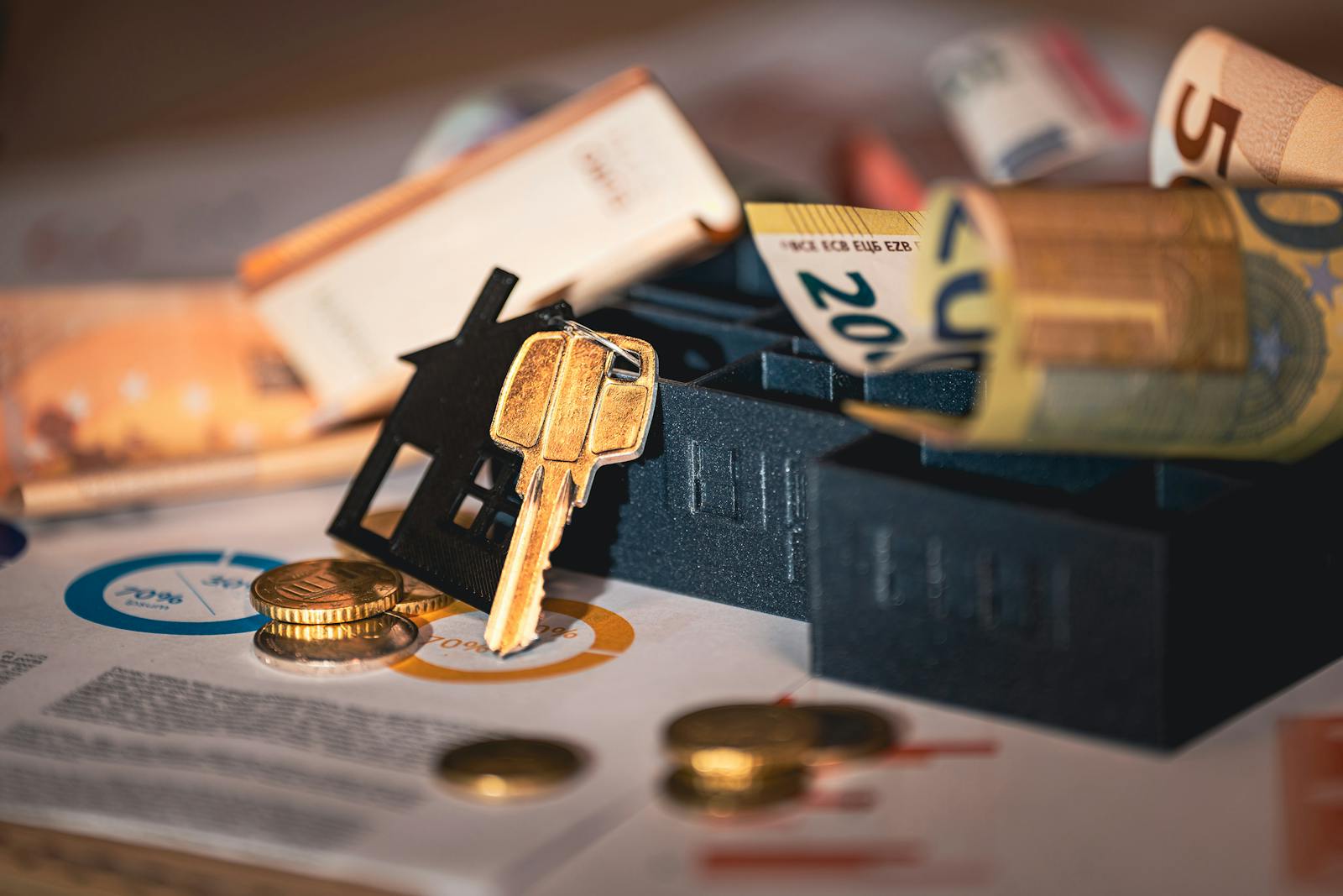 Close-up of house keys, euro bills, and charts symbolizing real estate investment and finance.